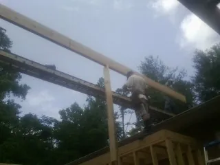 Carpenter setting a ridge beam over a new addition frame — Ice Dam Removal by Roofing Brothers in Okolona