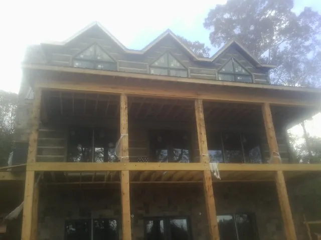 Dormers and porch framing on a large log home under construction — Roof Coating work by our crew in Okolona