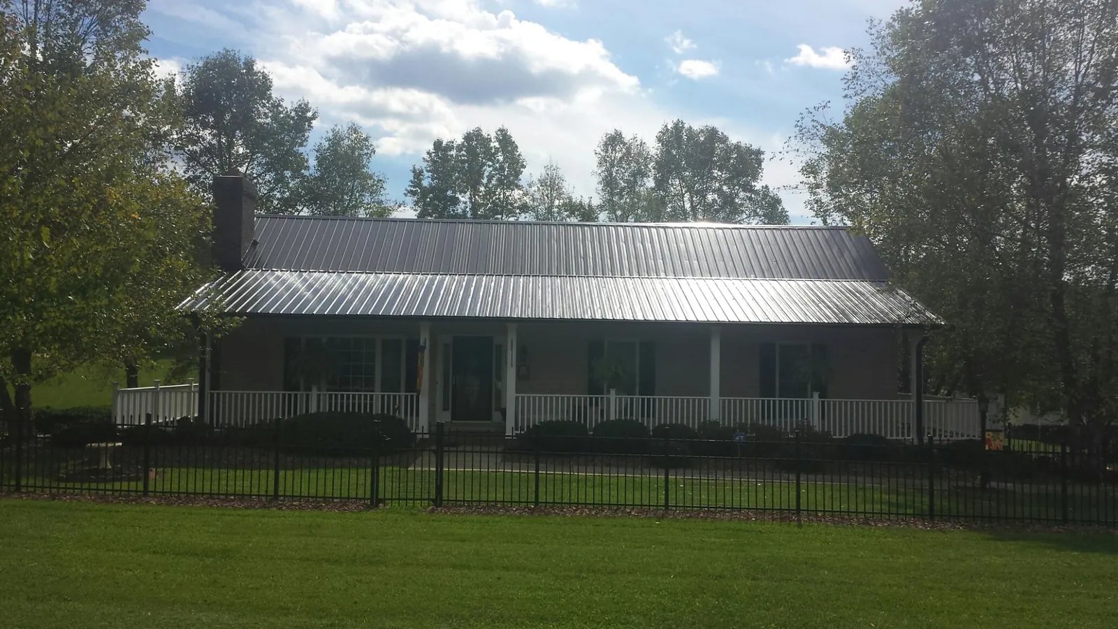 Gray metal roof on a brick ranch with a full width front porch — Gutter Guard Installation work by our crew in Okolona